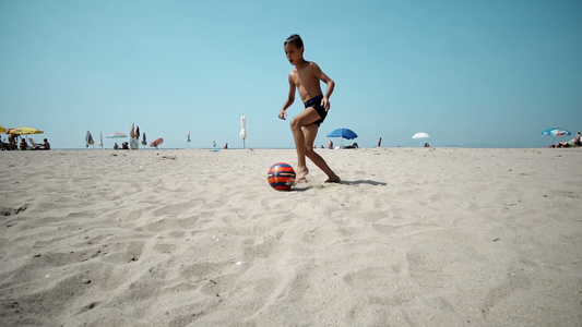 儿童在沙滩上踢足球慢动作视频