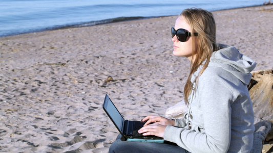 在海滩使用笔记本电脑的太阳镜上视频