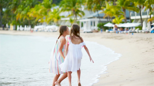 两个快乐的小女孩在热带沙滩玩耍时玩得开心极了视频
