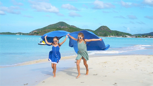 两个快乐的小女孩在热带沙滩玩耍时玩得开心极了视频