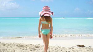 穿着大帽子的可爱小女孩在白沙滩上漫步16秒视频
