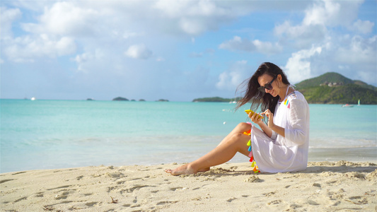 拥有智能手机的年轻女子在热带海滩度假视频