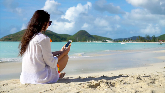 在热带海滩有电话的年轻女子视频