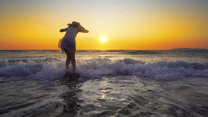 戴着帽子的年轻女士站在沙沙海滩的水里仰望天空24秒视频