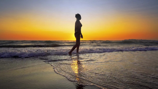 性感女人在海滨日落时在水上行走的电影镜头Stadicam视频