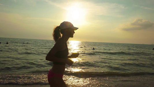 戴帽子的年轻运动女青年在日出日落时正在海上参加体操比赛视频
