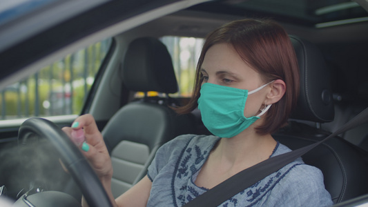 戴面罩的年轻女子在车内使用洗手液洗手和方向盘女司机视频