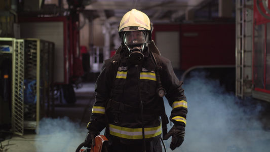 消防员肖像穿着全套设备氧气面罩和动力液压切割工具烟雾视频
