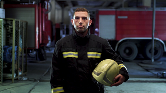 消防员视频肖像身穿制服持有黄色防护头盔背景的消防车视频