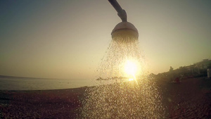 夏日概念慢动作沙滩头冲浴用自来水对抗日落的太阳20秒视频