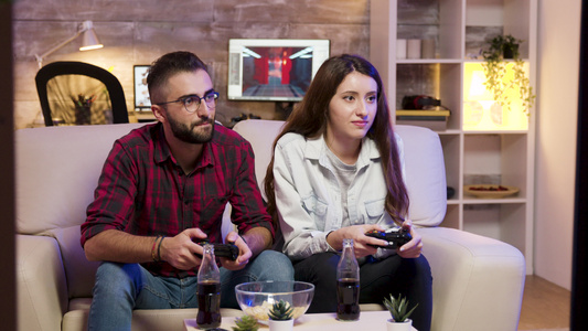快乐的年轻情侣坐在一对情侣上玩电子游戏视频