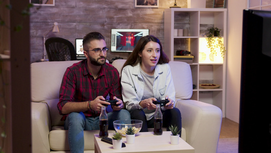 坐在沙发上玩电子游戏的一对快乐的年轻夫妇视频