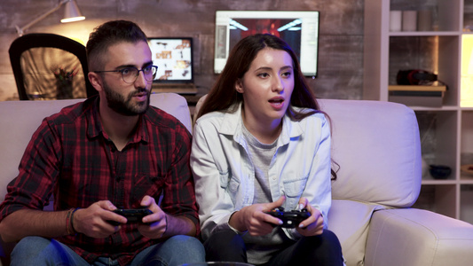 一对夫妇坐在沙发上放松玩电子游戏视频