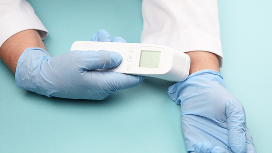 一名蓝乳胶手套医生用非接触温度计顶视测量手腕的体温视频