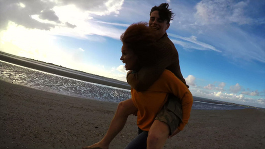 女人背着男人在沙滩上奔跑视频
