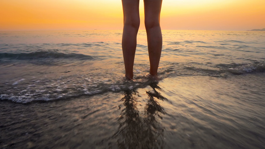 海滩日落时女人的脚被海浪溅起在美丽的海滩上海水溅在视频