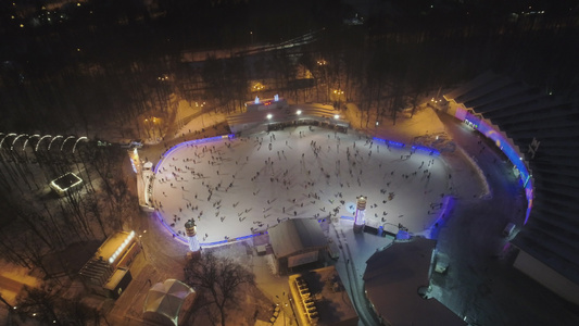 晚上一群人在大型照明溜冰场上滑冰圣诞节的时候鸟瞰图视频