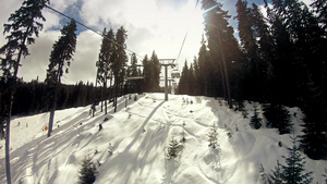 日出时在阳光明媚的冬季日子里滑雪者骑着椅子升降机慢动作21秒视频