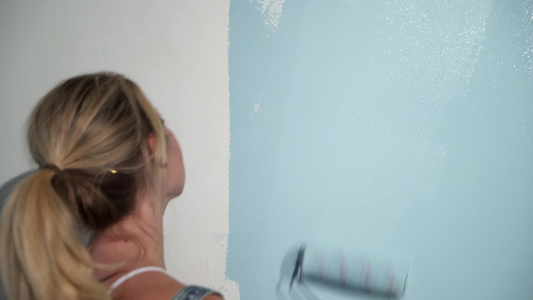在建筑工地用涂漆滚滚粉的年轻女孩建筑商视频
