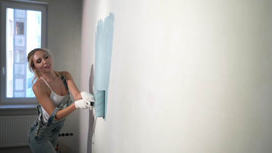 在建筑工地用涂漆滚滚粉的年轻女孩建筑商视频