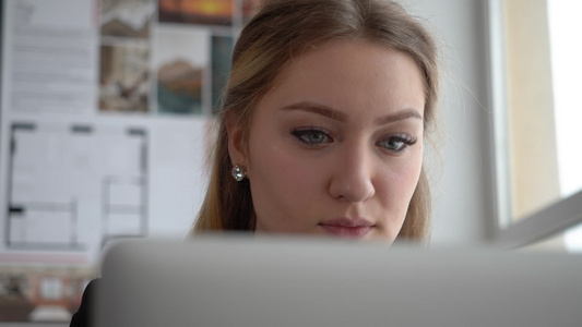 一名有吸引力的年轻商业女设计师在她办公室做笔记本电脑视频