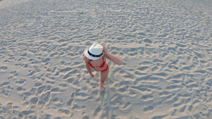身戴白帽子的年轻女子在阳光炎热的白天在海边海滩上行走20秒视频