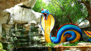 蓝黄色蛇模型在花园瀑布旁17秒视频