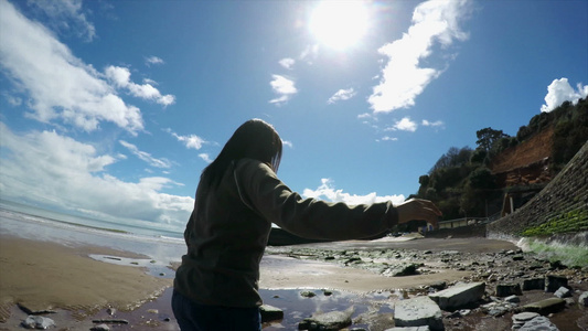 女人走在沙滩上的石头上视频