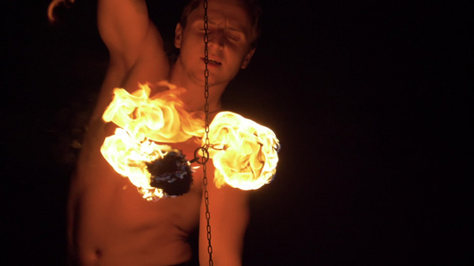 肌肉发达的男人正在表演火表演链上的两个火球正在旋转视频