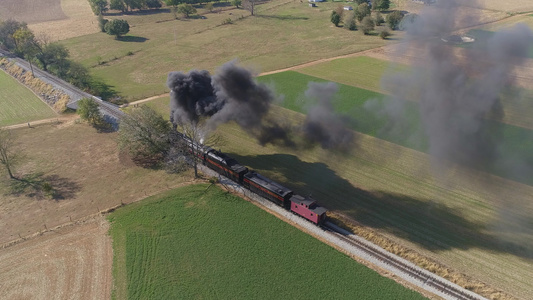 在美丽的秋天吹黑烟和蒸汽时农村停靠的蒸汽火车头部空中视频