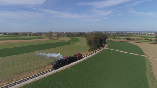 在农村喷发黑烟和蒸汽的恢复蒸汽机身后部的古董空中风景视频