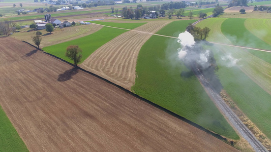 古董恢复蒸汽机的空中风景该蒸汽机在田地上飘散烟雾视频