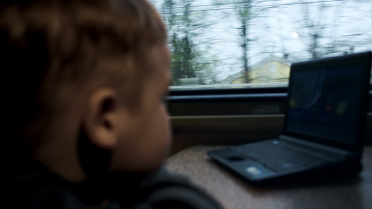 男孩在火车的笔记本电脑上观看电影或漫画视频