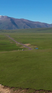 航拍巴音布鲁克草原上穿行的独库公路视频天山山脉视频