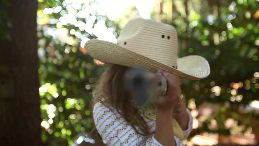 打扮成女牛仔的女孩用玩具步枪指着相机视频