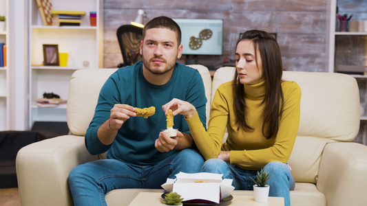 坐在沙发上吃炸鸡的年轻夫妇视频