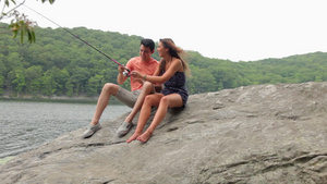 年轻夫妇在湖边的岩石上钓鱼18秒视频