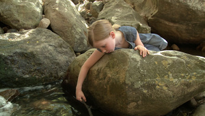 靠在河边岩石上玩耍的女孩11秒视频