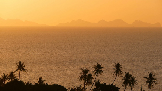 雄伟的热带橙色夏季海上实时日落与山脉剪影在海洋中的视频