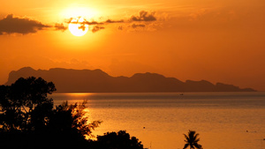 雄伟的热带橙色夏季海上实时日落与山脉剪影在海洋中的17秒视频