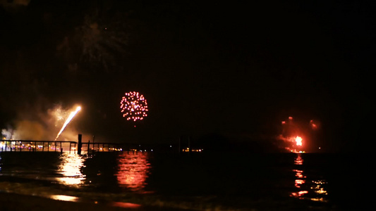 明亮的金烟花在海面上空的夜空中爆炸视频