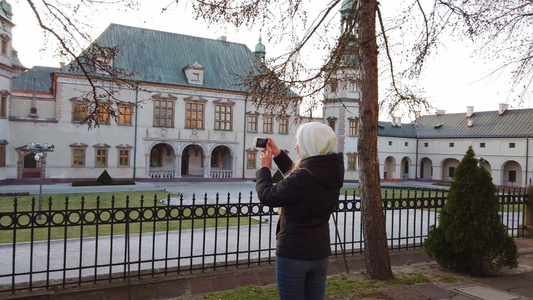 女游客在广场上拍下旧宫殿的照片视频