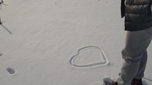 女人在冬天雪白雪上画了一颗心视频