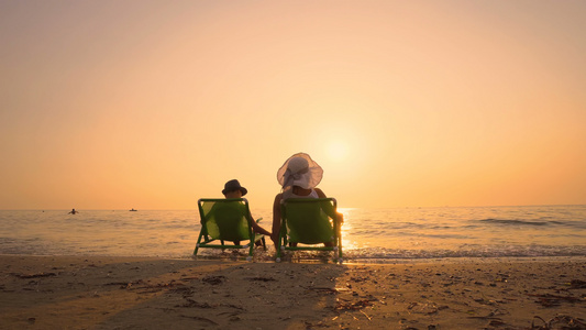 家庭在海上渡假他的儿子和母亲一起坐在日落海滩上视频