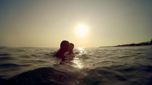 两个朋友父亲和儿子在日落时在海中交换情感慢动作视频