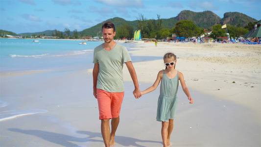 快乐的父亲和他可爱的小女儿在热带海滩散步一起走来走去视频