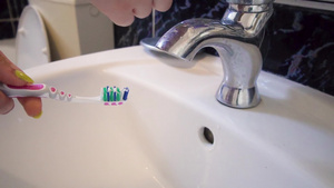 在自来自来水下洗牙刷的女子手工洗手慢动作30秒视频