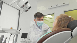 在他的诊所工作的男牙医检查一个小女孩的牙齿18秒视频