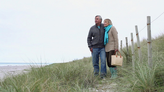 一对夫妇站在海岸的沙丘上视频