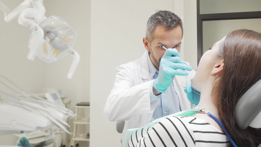 成熟男性牙医检查女性患者的牙齿视频